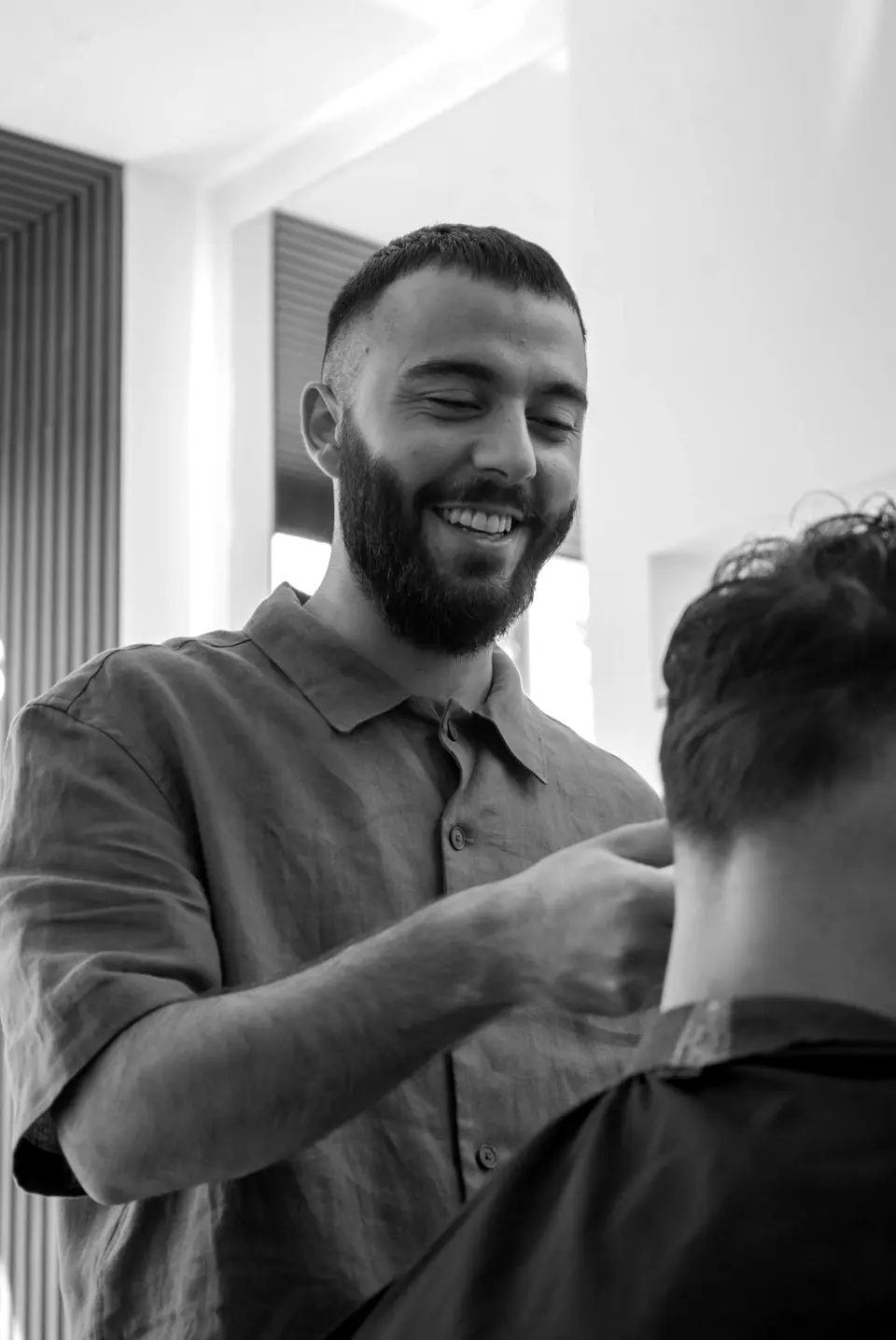 Kadir Simsek lacht tijdens het knippen in zijn salon in Laren