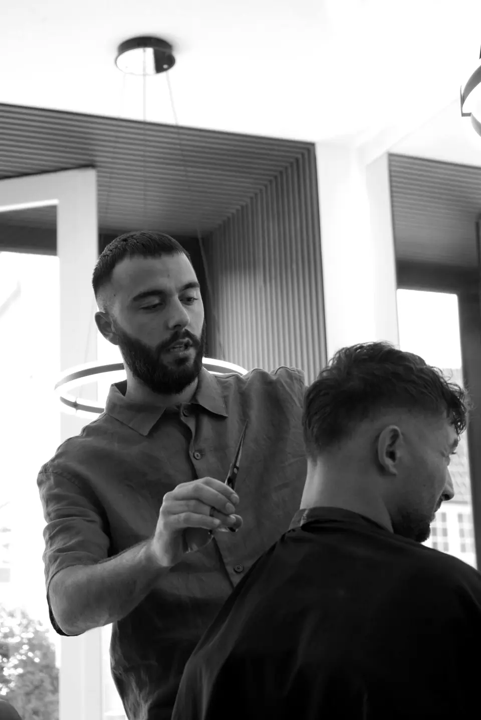Kadir knipt een klant met de schaar in de salon in Laren