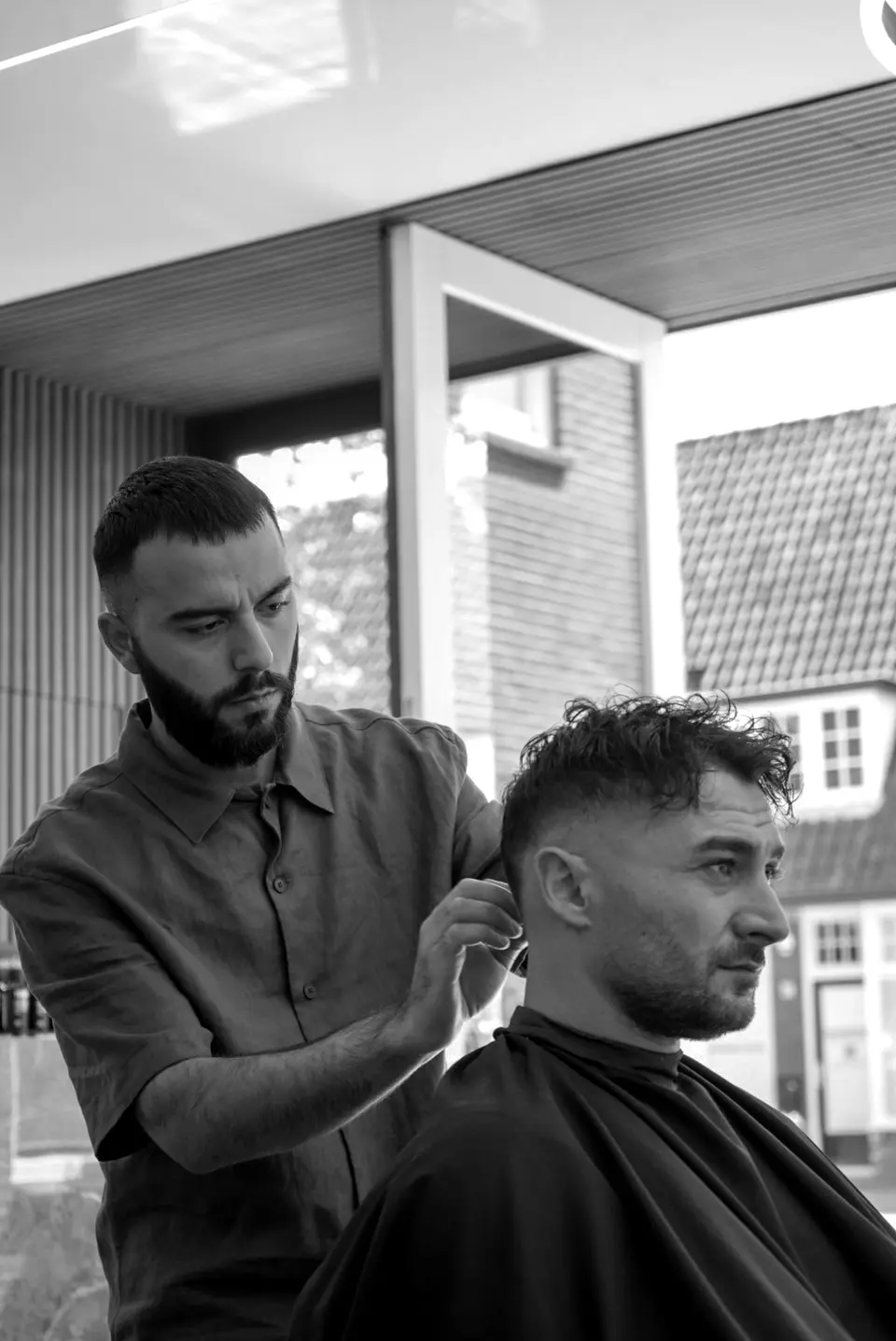 Kadir knipt een klant met krullen in de salon
